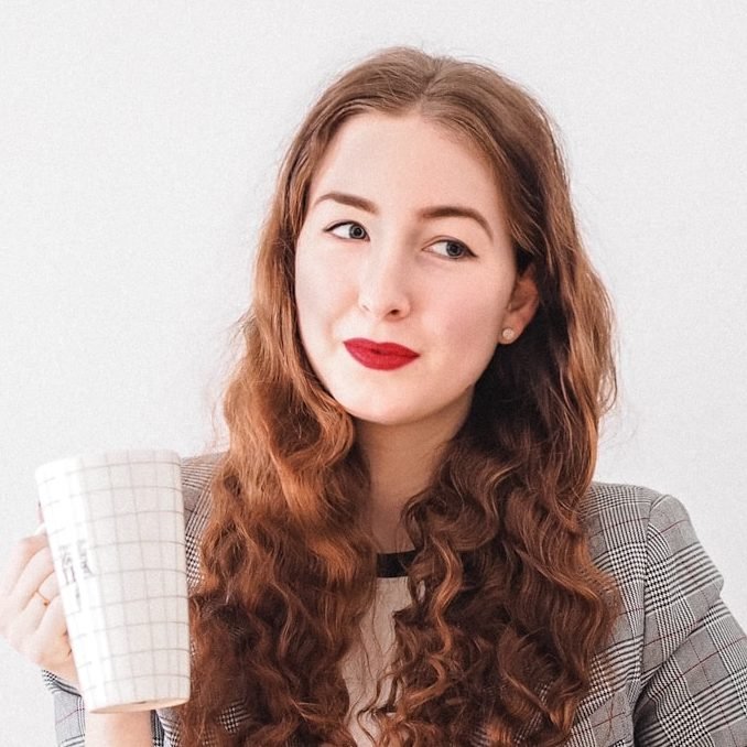 woman in gray cardigan holding white ceramic mug